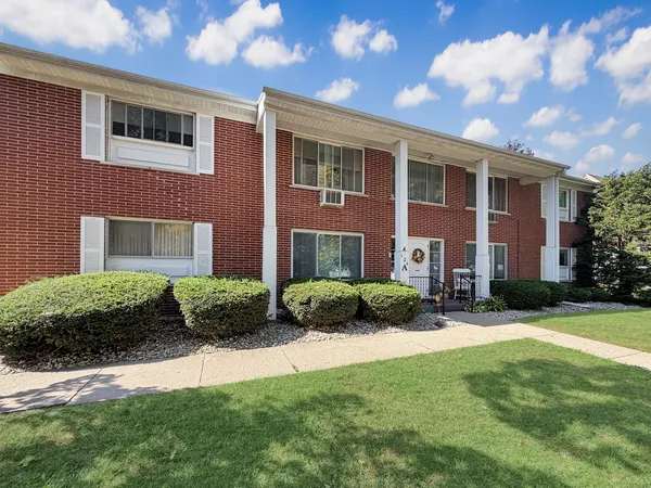 a view of a brick house with a yard and plants
