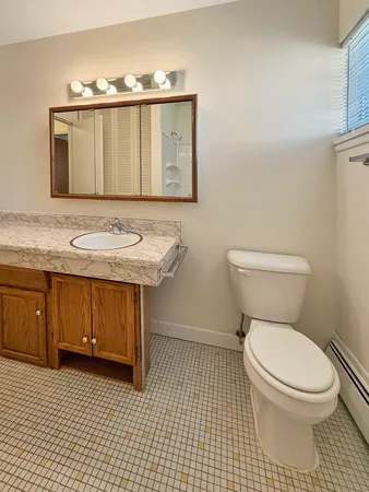 a bathroom with a granite countertop toilet sink and mirror