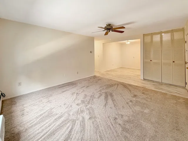 an empty room with wooden floor fan and windows