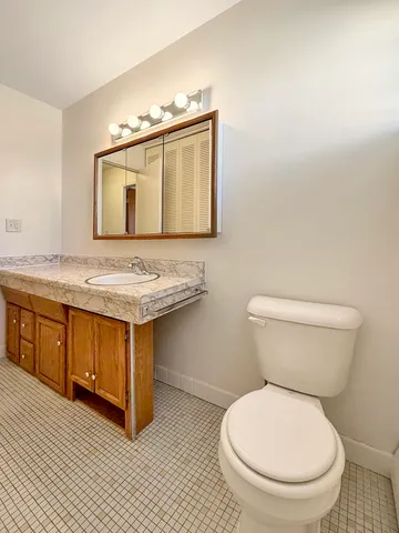 a bathroom with a granite countertop toilet sink and mirror