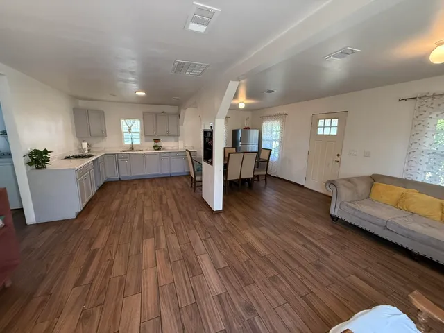 a large living room with a couch wooden floor and a view of kitchen