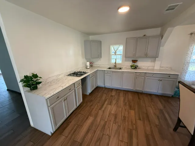 a kitchen with granite countertop a sink and cabinets with wooden floor