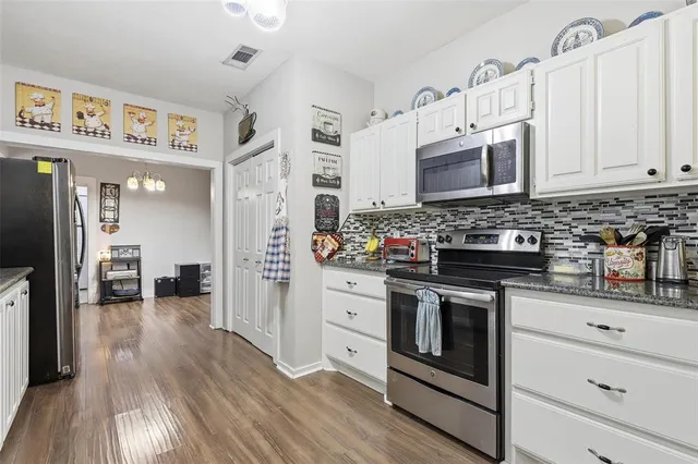 a kitchen with stainless steel appliances granite countertop a stove and cabinets