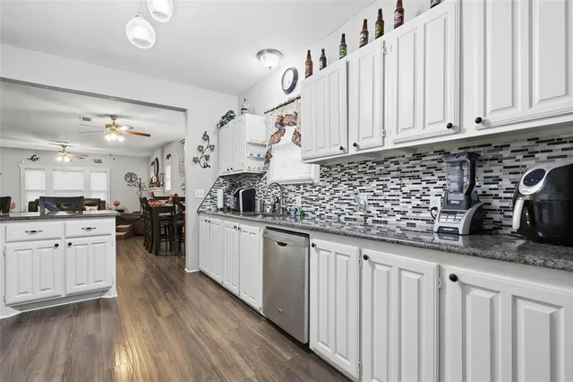 a kitchen with granite countertop a sink a stove cabinets and wooden floor