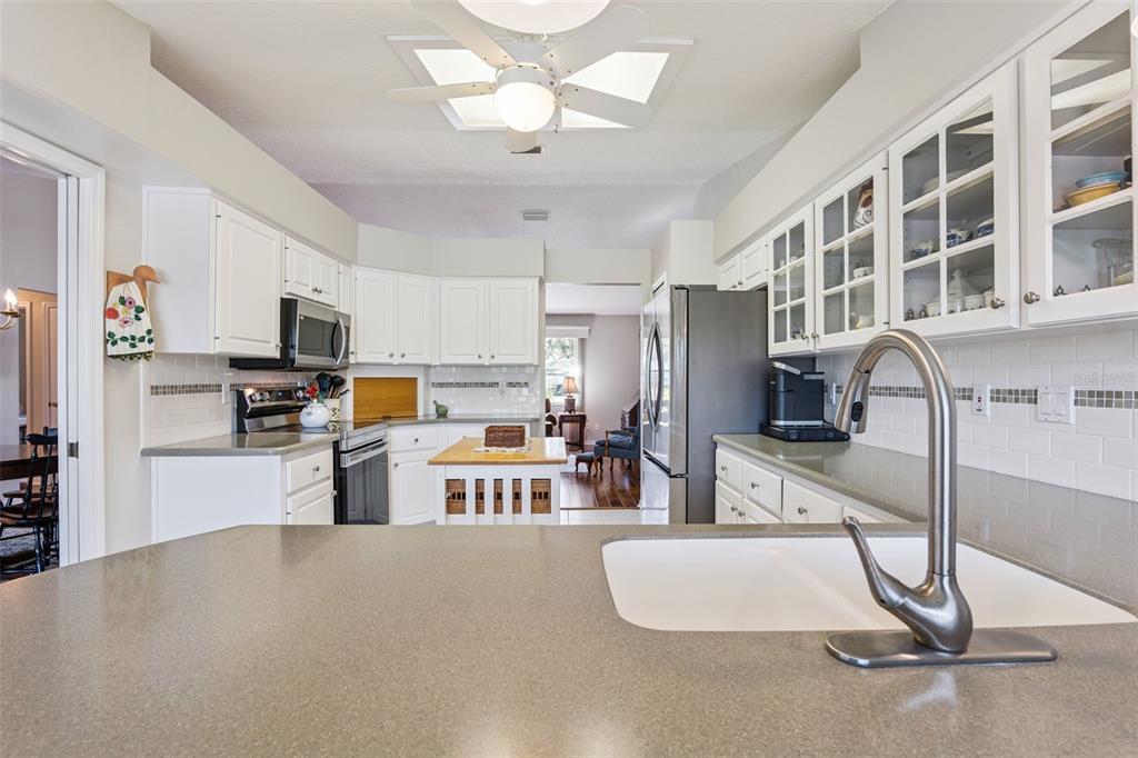 26450 Evert Street Leesburg, FL 34748 - Photo 16 of 93 a kitchen with stainless steel appliances granite countertop a refrigerator a stove a sink a microwave a dining table and chairs with wooden floor