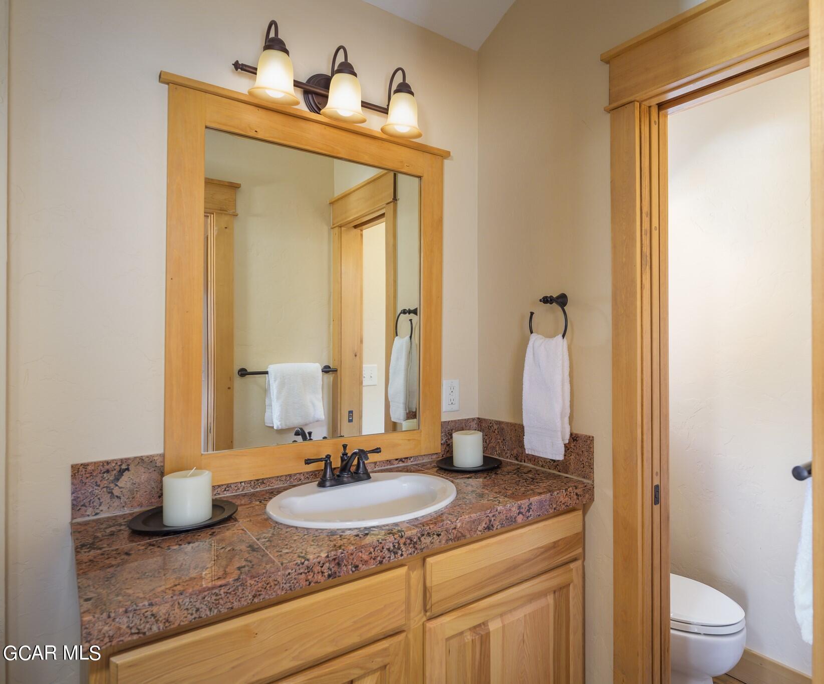 129 Edgewater Circle Granby, CO 80446 - Photo 21 of 63 a bathroom with a granite countertop sink and a mirror with toilet