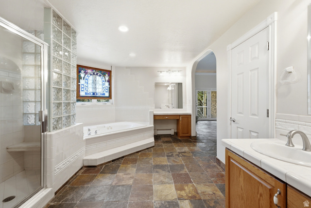 3535 Homestead Road Park City, UT 84098 - Photo 41 of 81 Spacious bathroom featuring natural stone flooring, a glass-enclosed shower with built-in bench, a jetted soaking tub, and dual vanity areas with solid surface countertops