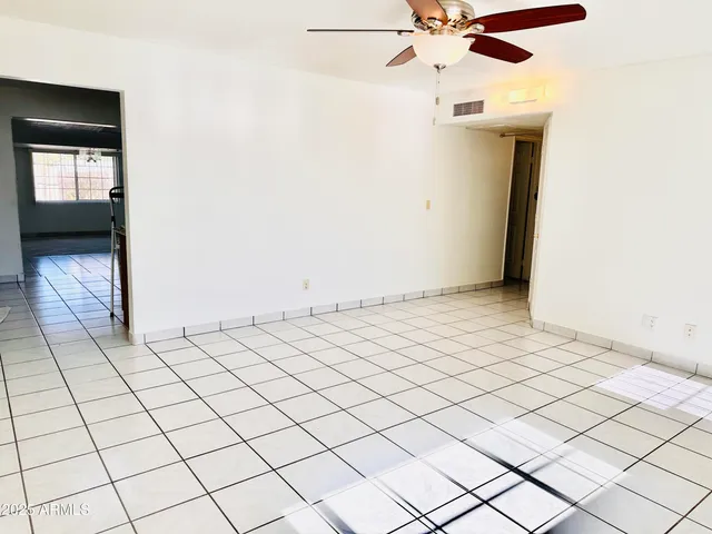 an empty room with windows and fan