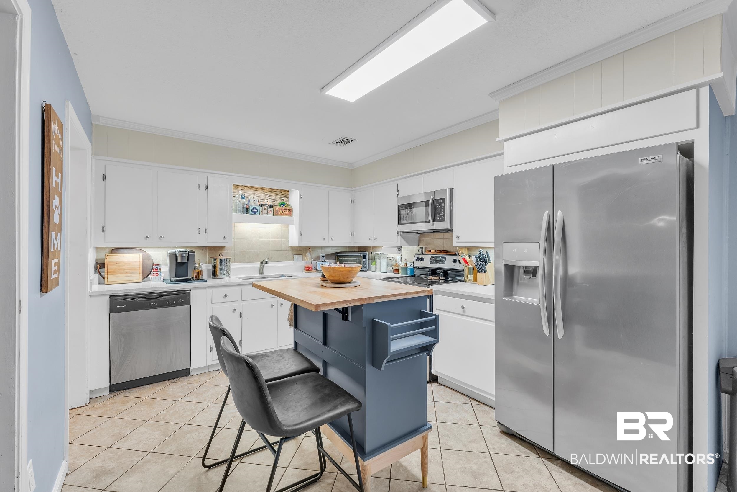 206 West Jackson Avenue Summerdale, AL 36580 - Photo 13 of 37 Kitchen featuring stainless steel appliances, a sink, white cabinetry, light tile patterned floors, and tasteful backsplash