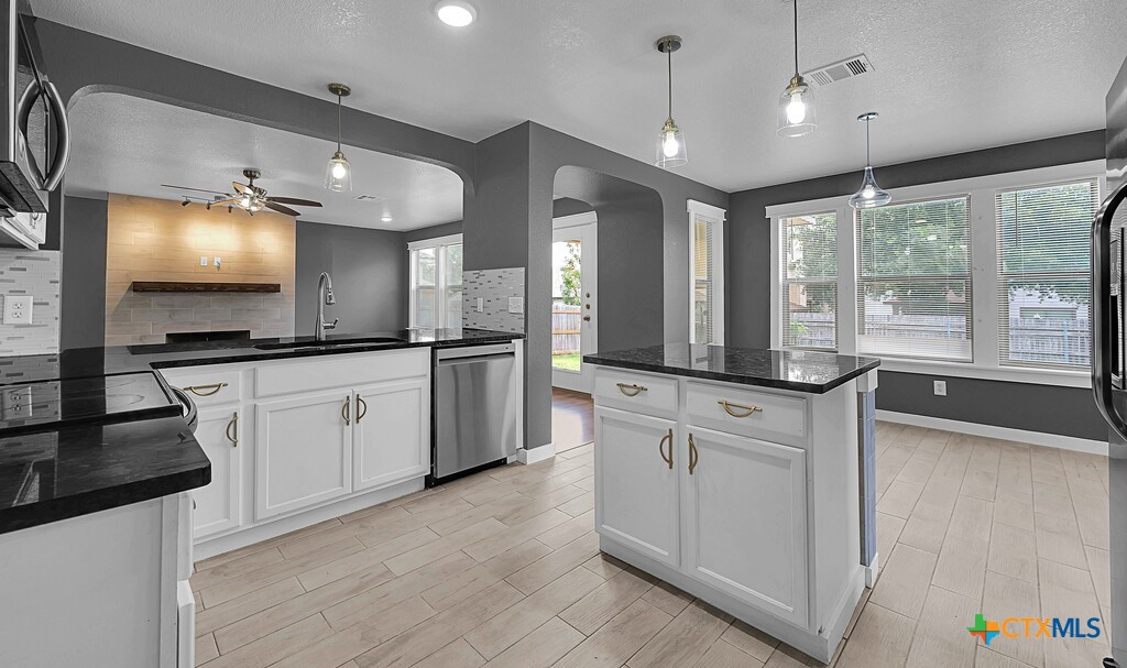 a large kitchen with granite countertop a large window and white cabinets