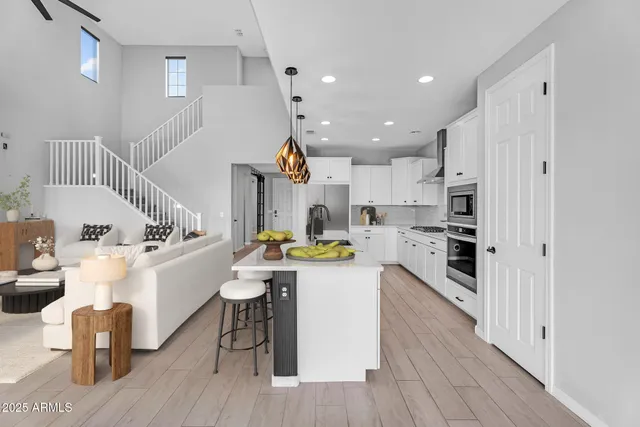 a kitchen with a refrigerator a stove and white cabinets with wooden floor