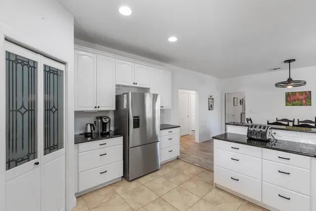 a kitchen with stainless steel appliances granite countertop a stove top oven a sink dishwasher a dining table and chairs with wooden cabinets