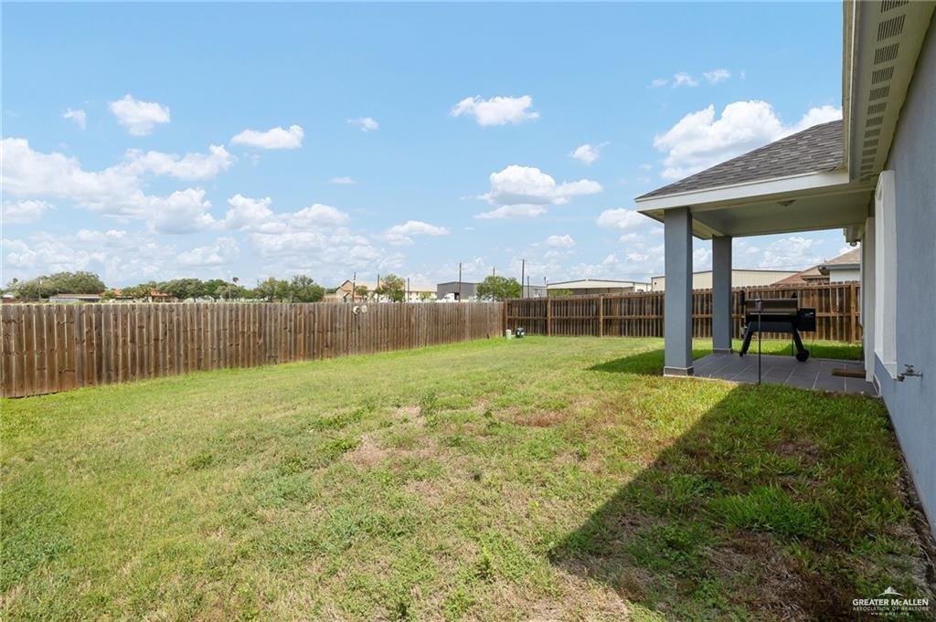 521 Oak Ridge Street Donna, TX 78537 - Photo 18 of 21 Expansive backyard with a covered patio, concrete slab, and wood privacy fencing