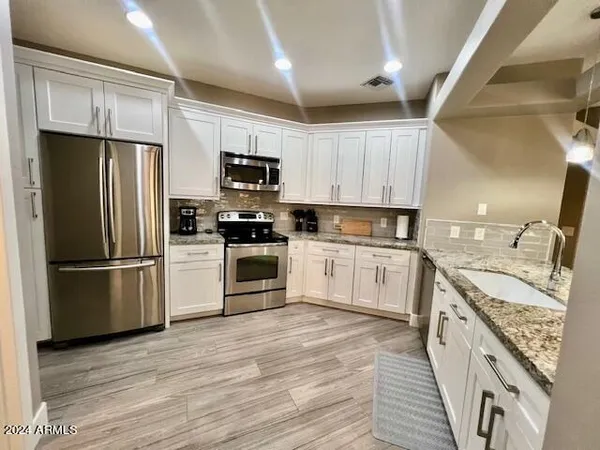 a kitchen with stainless steel appliances granite countertop a refrigerator a stove top oven a sink and dishwasher