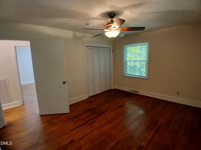 a view of an empty room with wooden floor and a window