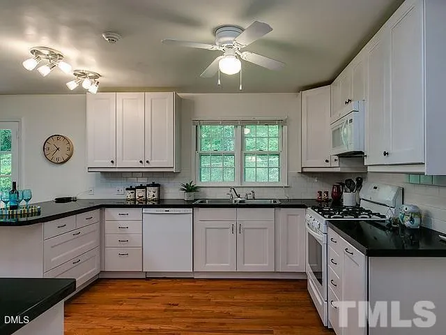 a kitchen with granite countertop a sink a stove cabinets and a window