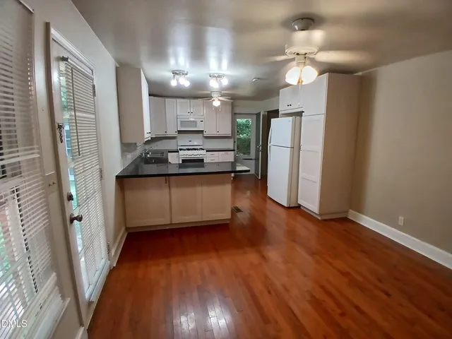 a kitchen with stainless steel appliances granite countertop a refrigerator a sink dishwasher a stove and white countertops with wooden floor