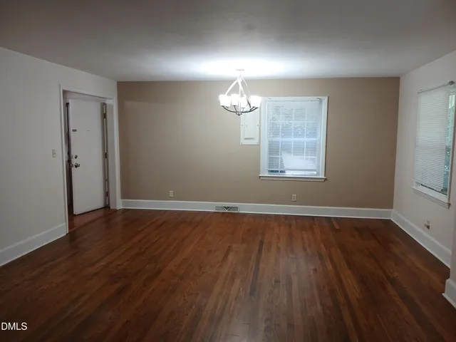 an empty room with wooden floor chandelier fan and windows