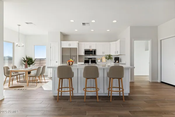 a kitchen with stainless steel appliances granite countertop a dining table chairs refrigerator microwave and cabinets