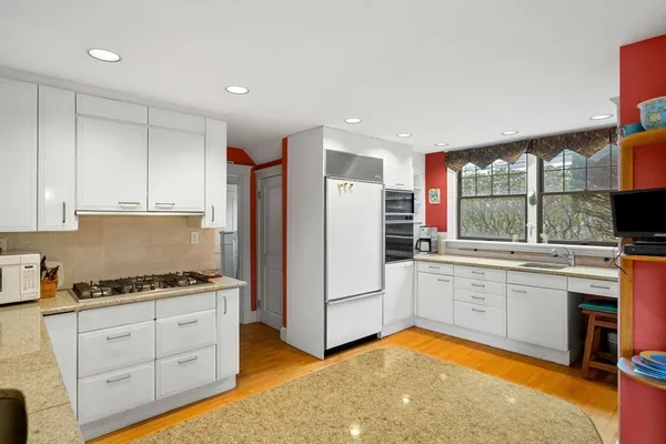 a kitchen with stainless steel appliances granite countertop a stove a sink dishwasher and a refrigerator with wooden floor