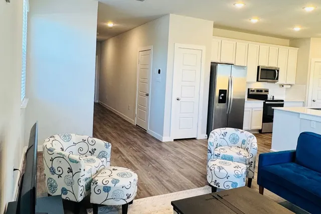 a kitchen with a refrigerator a stove top oven a sink dishwasher and white cabinets with wooden floor