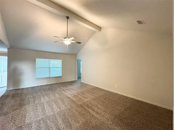 an empty room with a chandelier fan and windows