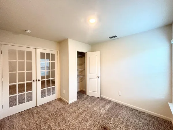an empty room with a chandelier fan and glass door