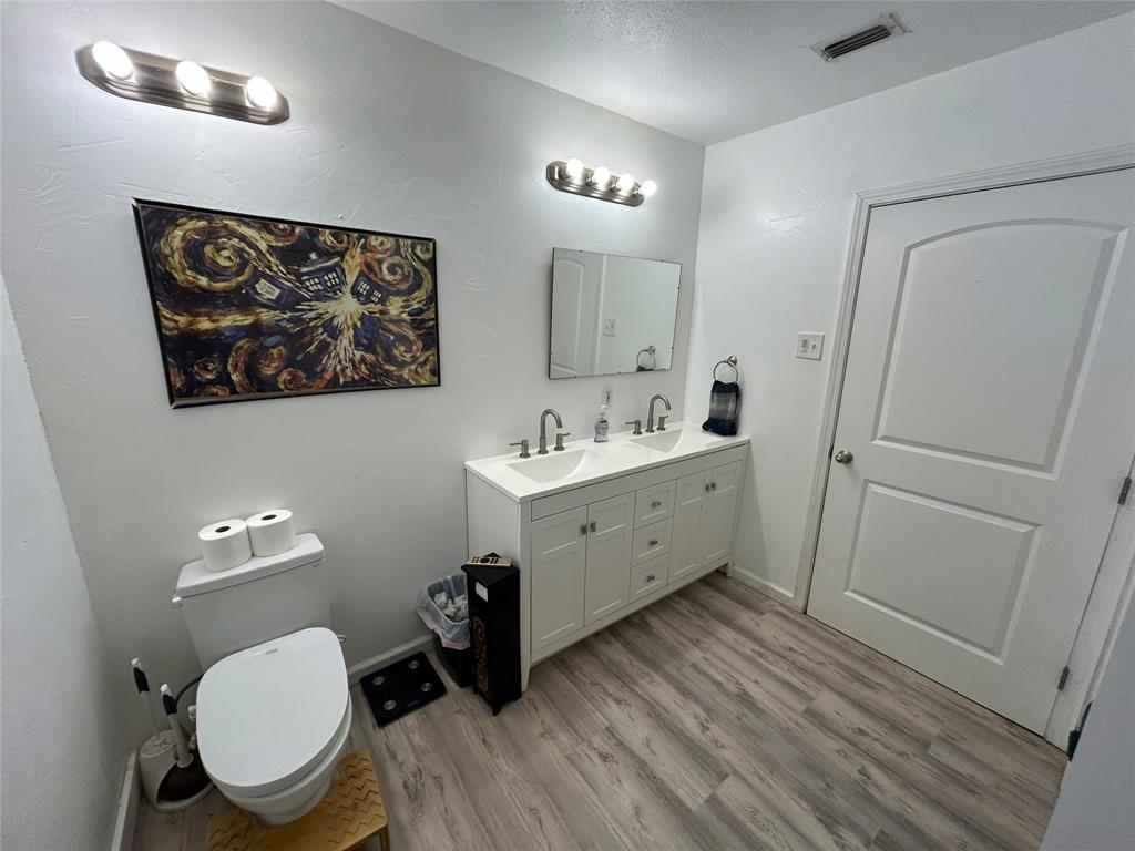 724 South Rusk Street Gainesville, TX 76240 - Photo 15 of 29 a bathroom with a toilet a sink and mirror