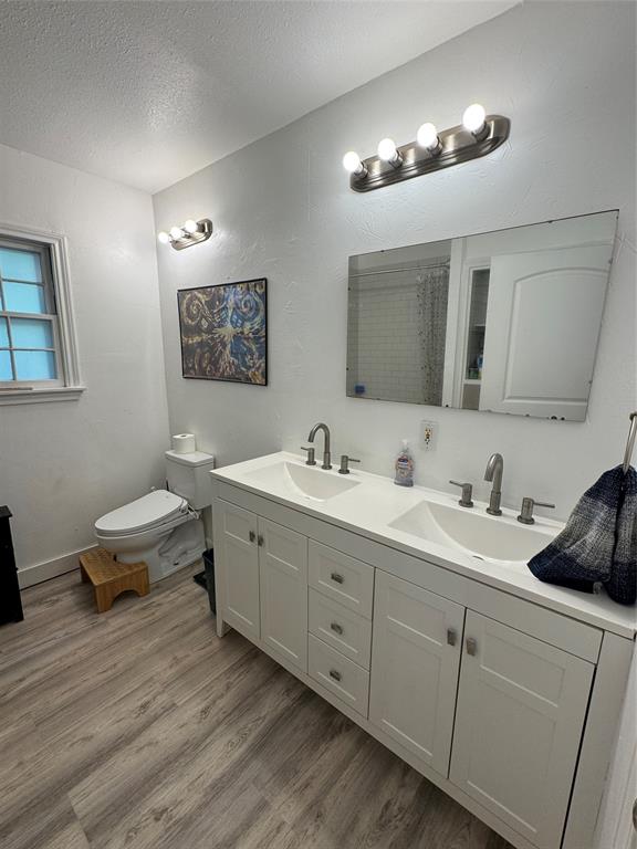 724 South Rusk Street Gainesville, TX 76240 - Photo 16 of 29 a spacious bathroom with a double vanity sink a mirror and a toilet