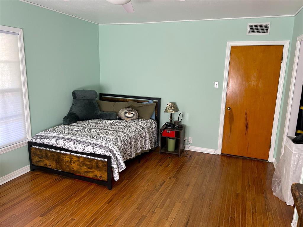 724 South Rusk Street Gainesville, TX 76240 - Photo 21 of 29 a bedroom with a bed and wooden floor