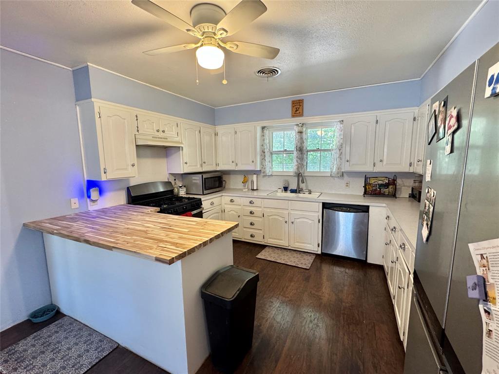 724 South Rusk Street Gainesville, TX 76240 - Photo 9 of 29 a kitchen that has a lot of cabinets a sink a stove and wooden floor