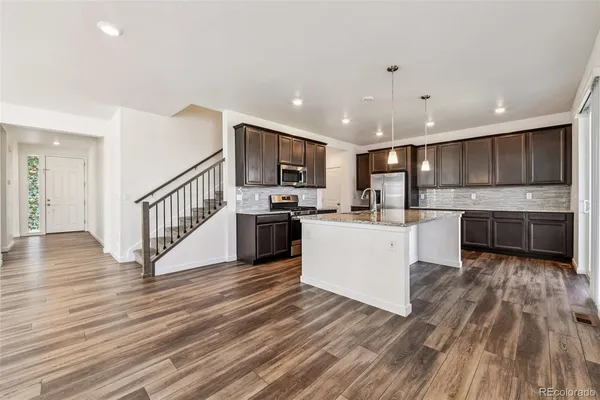 a kitchen with wooden floors stainless steel appliances and white cabinets