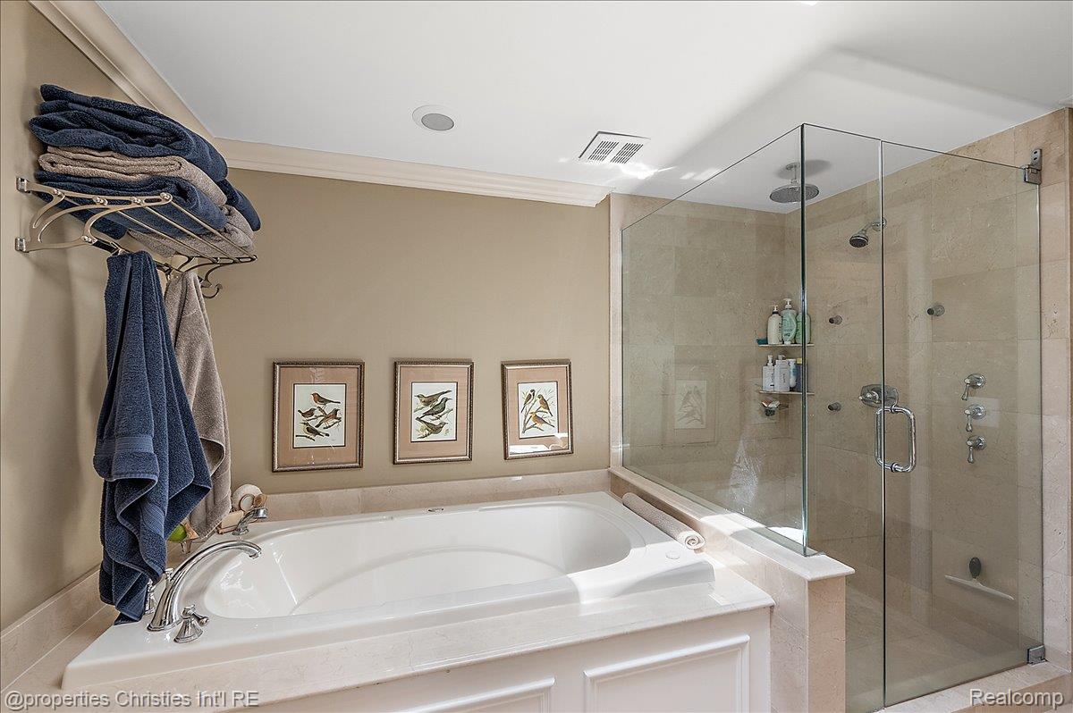 135 Clifton Road Bloomfield Hills, MI 48301 - Photo 40 of 77 Soaking tub with chrome fixtures, surrounded by a light-toned stone deck