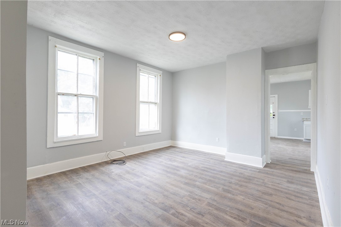 11838 Triskett Road Cleveland, OH 44111 - Photo 9 of 20 Spare room featuring a textured ceiling, hardwood floors, and a healthy amount of sunlight