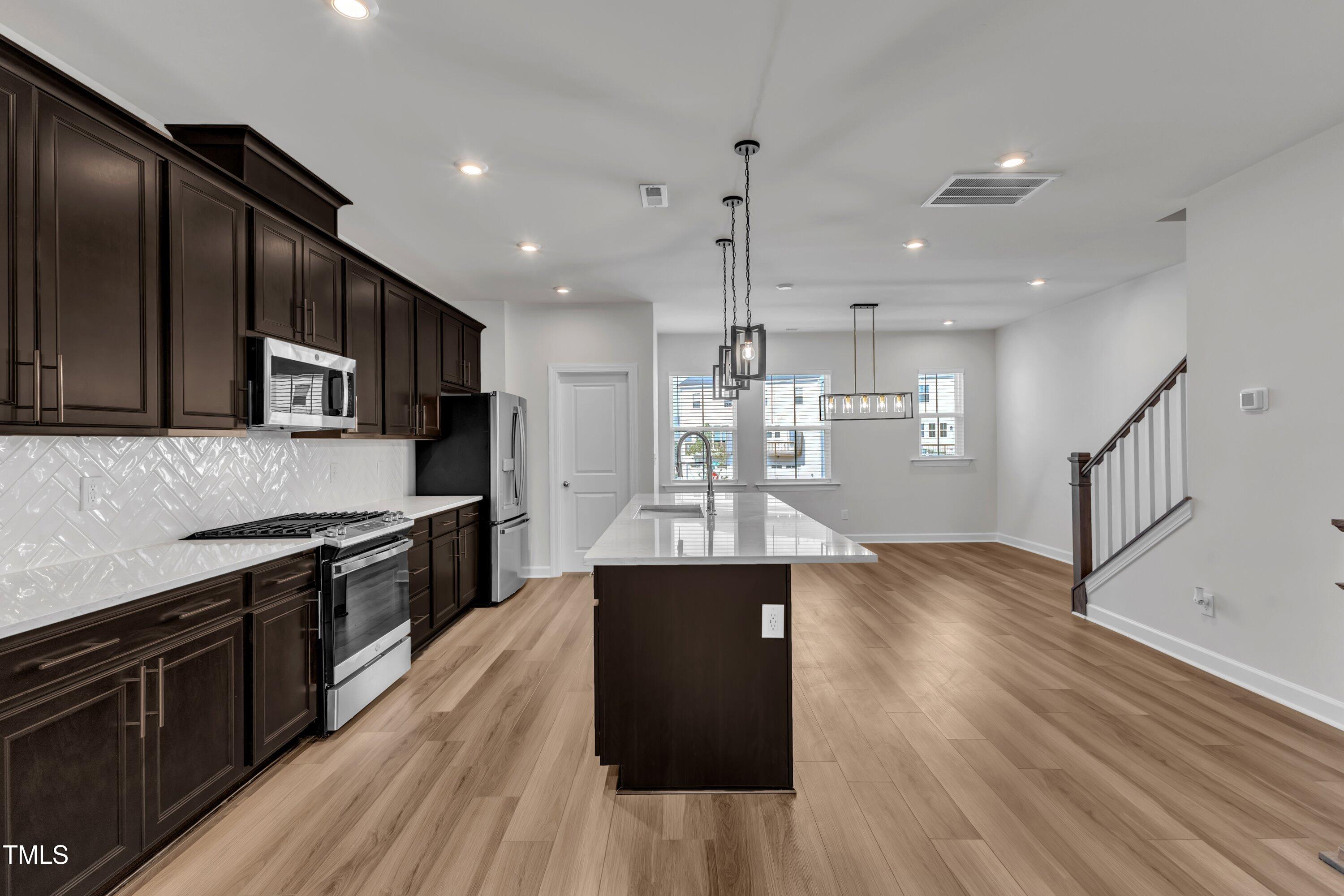 816 Lilyquist Way Wake Forest, NC 27587 - Photo 18 of 53 a large kitchen with stainless steel appliances kitchen island granite countertop a large counter top and wooden floors