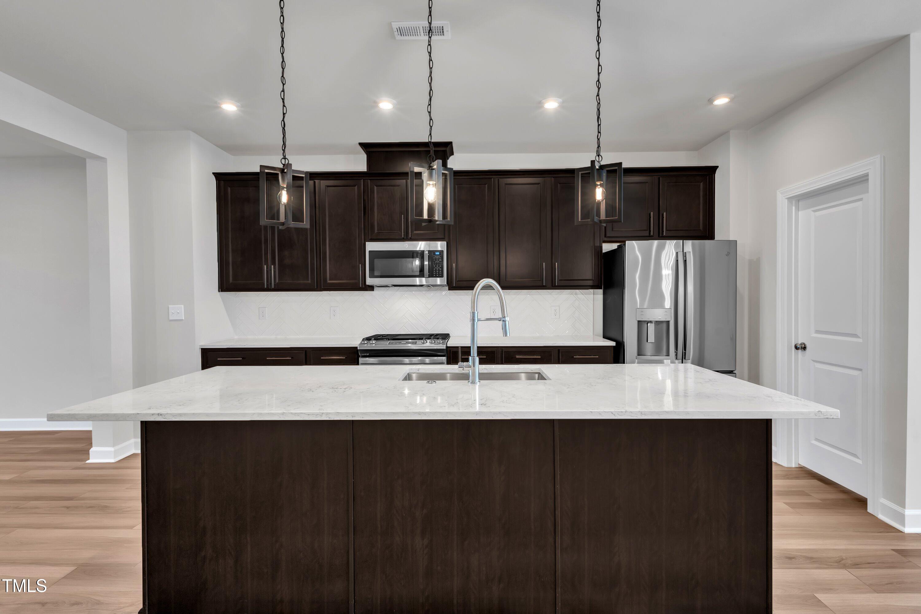 816 Lilyquist Way Wake Forest, NC 27587 - Photo 20 of 53 a large kitchen with kitchen island granite countertop a refrigerator a stove a sink and a oven with wooden floor