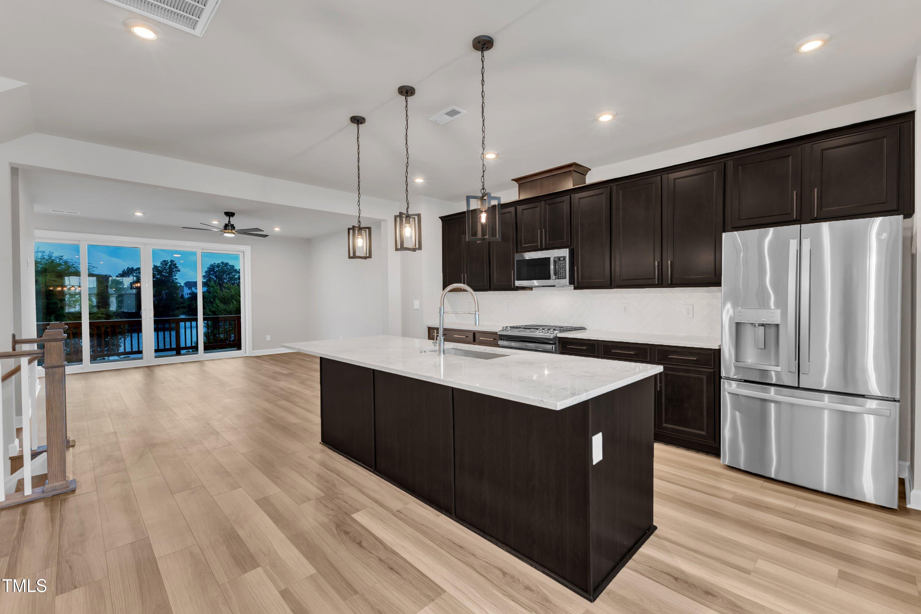 816 Lilyquist Way Wake Forest, NC 27587 - Photo 21 of 53 a kitchen with stainless steel appliances kitchen island granite countertop a stove a refrigerator a sink and dishwasher with wooden floor