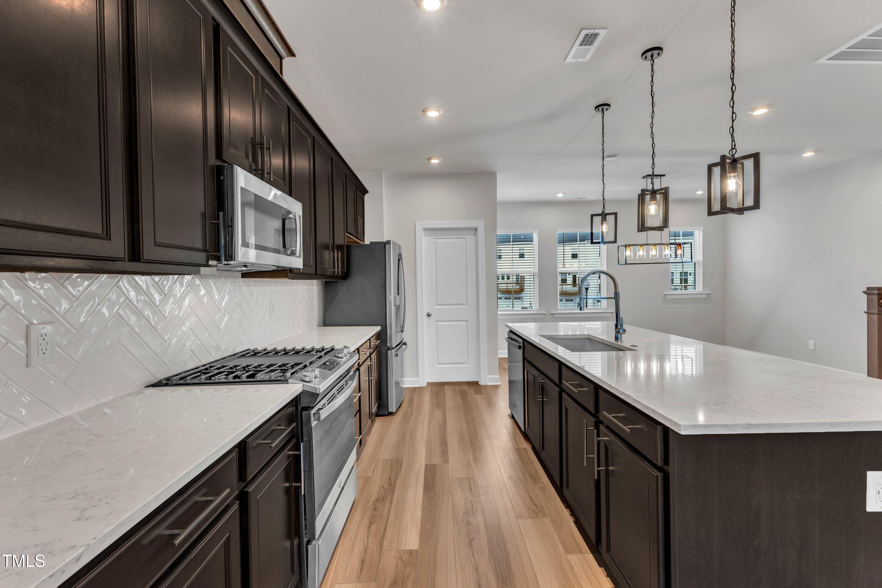 816 Lilyquist Way Wake Forest, NC 27587 - Photo 22 of 53 a kitchen with granite countertop stainless steel appliances lots of counter space and wooden floor
