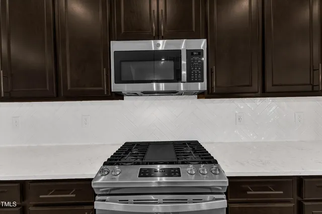 a kitchen with a sink a microwave a refrigerator and chairs