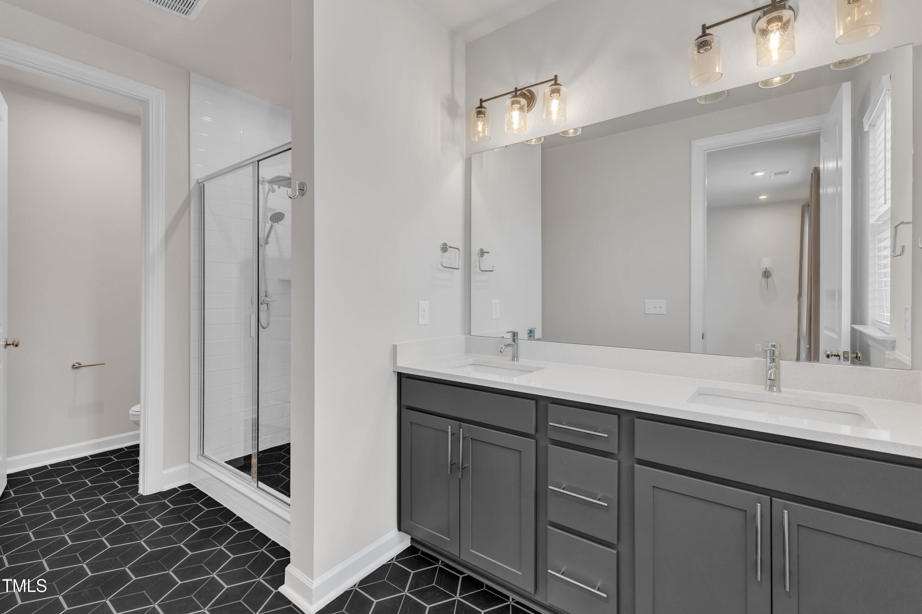 816 Lilyquist Way Wake Forest, NC 27587 - Photo 31 of 53 a spacious bathroom with a double vanity sink a mirror and a shower