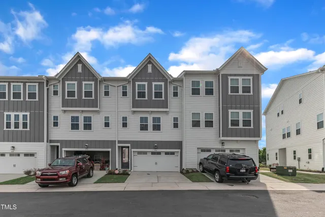 a front view of a building with lot of cars and trees