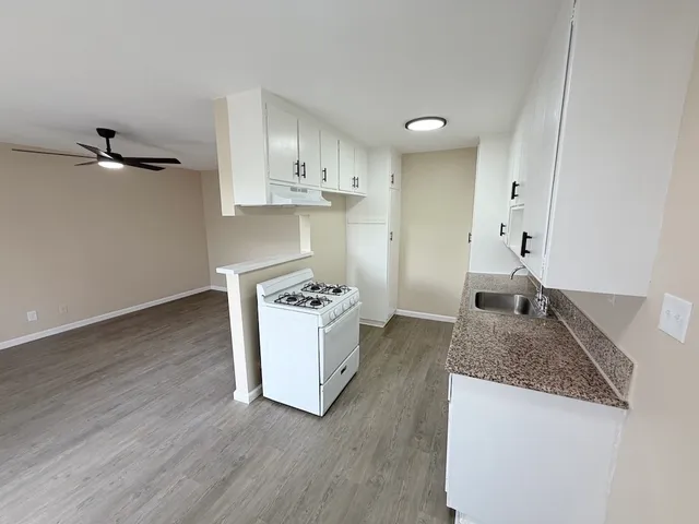 a kitchen with granite countertop a sink stove and refrigerator