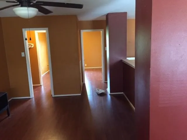 an empty room with wooden floor and a ceiling fan