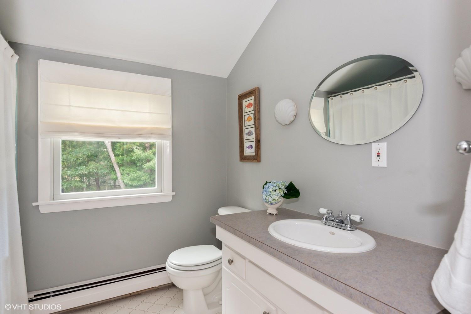 1166 Old Post Road Cotuit, MA 02635 - Photo 12 of 15 a bathroom with a toilet a sink a mirror and a window