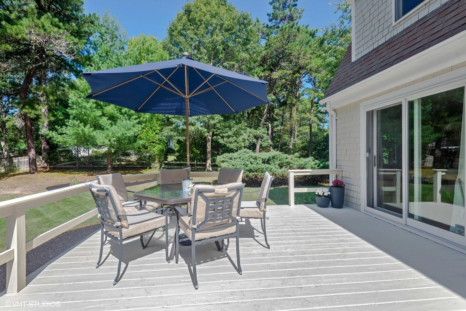 1166 Old Post Road Cotuit, MA 02635 - Photo 14 of 15 a patio with wooden floor a yard a table and chairs