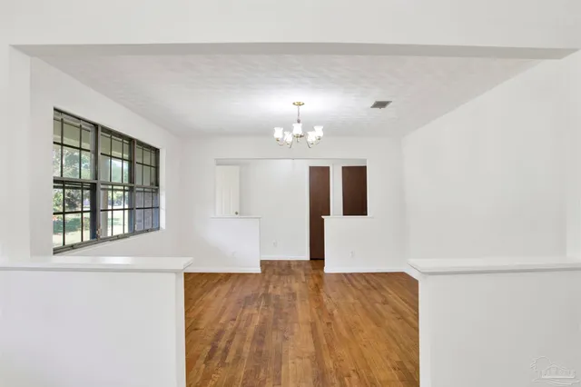 a view of empty room with wooden floor and window
