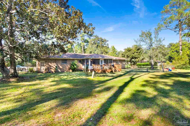 a view of swimming pool with lawn chairs and large trees