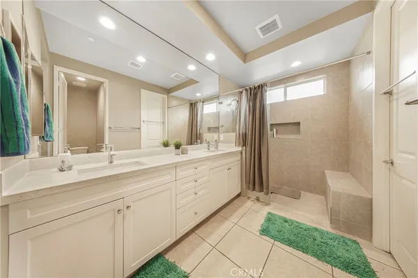 a spacious bathroom with a double vanity sink a mirror and a shower