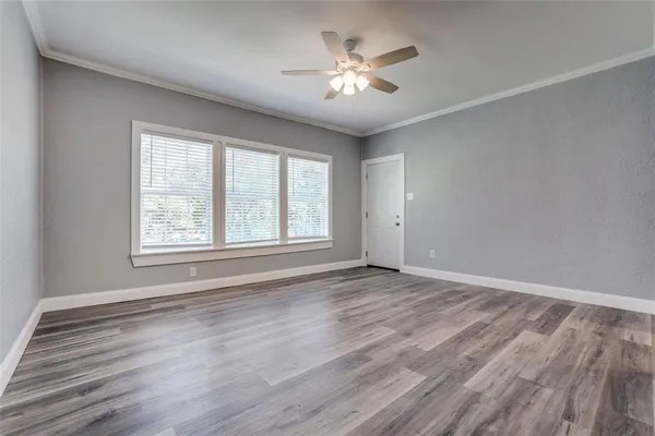 a view of an empty room with a window and wooden floor