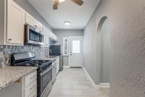 a kitchen with stainless steel appliances granite countertop a stove a sink and a microwave